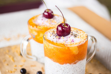 Chia pudding with mango, papaya topping and cherry on the top in the glass. raw vegan vegetarian food and drinks. Healthy sweet dessert without sugar with bananas. Trendy style and paleo diet.