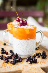Chia pudding with mango, papaya topping and cherry on the top in the glass. raw vegan vegetarian food and drinks. Healthy sweet dessert without sugar with bananas. Trendy style and paleo diet.
