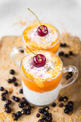 Chia pudding with mango, papaya topping and cherry on the top in the glass. raw vegan vegetarian food and drinks. Healthy sweet dessert without sugar with bananas. Trendy style and paleo diet.
