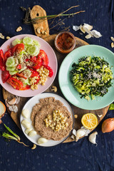 Vegan vegetarian lunch or dinner with vegetables salads, homemade whole wheat breads and tomato sauce paste. Raw healthy food. Paleo trendy diet.