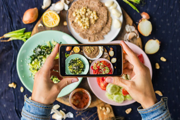 Smartphone food photography of vegetarian lunch or dinner. Woman hands taking phone photo of food...