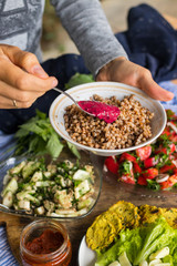 Woman hands spreading tomato dip sauce with sour plums and ajika on Russian traditional buckwheat porridge. Raw vegan vegetarian food. Healthy paleo diet. Trendy dieting