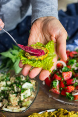 Woman hands spreading tomato dip sauce with sour plums and ajika on small homemade bread of whole wheat on salad leave. Raw vegan vegetarian food. Healthy paleo diet. Trendy dieting