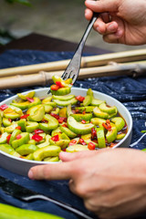 Woman hands holds asian cucumber red bell pepper and chilly hot pepper salad with soy sauce. Authentic Thai food menu. Raw vegan vegetarian healthy food