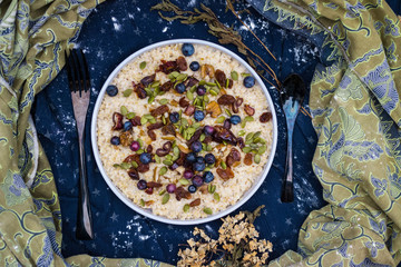 Oatmeal granola porridge with banana, dried fruits, honey and berries. Dates, dried grape, honey, blueberry, raspberry and oats for morning breakfast. Vegan vegetarian healthy food and paleo diet