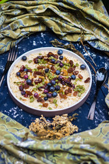Oatmeal granola porridge with banana, dried fruits, honey and berries. Dates, dried grape, honey, blueberry, raspberry and oats for morning breakfast. Vegan vegetarian healthy food and paleo diet