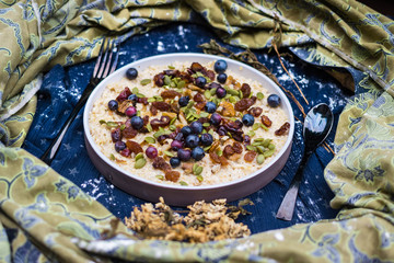 Oatmeal granola porridge with banana, dried fruits, honey and berries. Dates, dried grape, honey, blueberry, raspberry and oats for morning breakfast. Vegan vegetarian healthy food and paleo diet