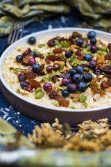 Oatmeal granola porridge with banana, dried fruits, honey and berries. Dates, dried grape, honey, blueberry, raspberry and oats for morning breakfast. Vegan vegetarian healthy food and paleo diet