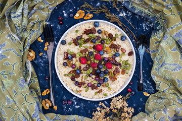 Oatmeal granola porridge with banana, dried fruits, honey and berries. Dates, dried grape, honey, blueberry, raspberry and oats for morning breakfast. Vegan vegetarian healthy food and paleo diet