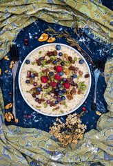 Oatmeal granola porridge with banana, dried fruits, honey and berries. Dates, dried grape, honey, blueberry, raspberry and oats for morning breakfast. Vegan vegetarian healthy food and paleo diet