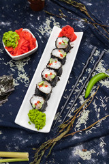 Homemade vegetarian sushi rolls with chopsticks with tofu, rice, cucumber, avocado, carrot, sour gari - pickled red ginger and wasabi wrapped into nori seaweed. Raw vegan vegetarian healthy food