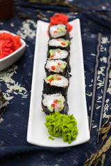 Homemade vegetarian sushi rolls with chopsticks with tofu, rice, cucumber, avocado, carrot, sour gari - pickled red ginger and wasabi wrapped into nori seaweed. Raw vegan vegetarian healthy food