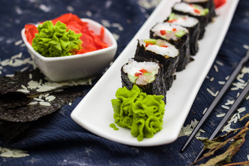Homemade vegetarian sushi rolls with tofu, rice, cucumber, avocado, carrot, sour gari - pickled red ginger and wasabi wrapped into nori seaweed. Raw vegan vegetarian healthy food