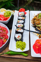 Homemade vegetarian sushi rolls with tofu, rice, cucumber, avocado, carrot, sour gari - pickled red ginger and wasabi wrapped into nori seaweed. Raw vegan vegetarian healthy food