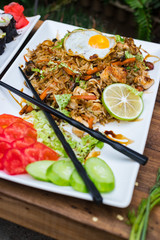Thai fried rice with egg on top served with vegetables - cucumber and tomato. Traditional asian food served at restaurants and cafes. Vegetarian food