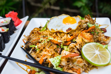 Thai fried rice with egg on top served with vegetables - cucumber and tomato. Traditional asian food served at restaurants and cafes. Vegetarian food