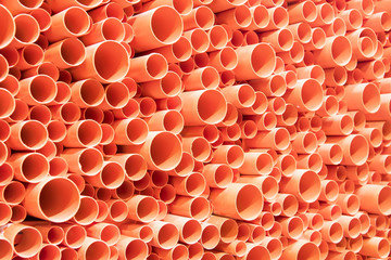orange PVC pipes stacked in construction site