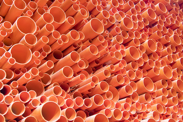 orange PVC pipes stacked in construction site