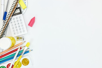 watercolor paints, pencils, notebook and other stationary for school on white background
