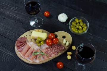 Appetizer on a wooden board with wine and olives for two. Romantic dinner