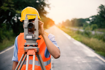 Survey by theodolite concept. Civil Engineer Checking Surveyor Equipment Tacheometer or theodolite outdoors at construction site on the road. - obrazy, fototapety, plakaty