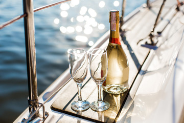 Romantic luxury evening on cruise yacht with champagne setting. Empty glasses and bottle with champagne and tropical sunset with sea background, nobody. - Powered by Adobe