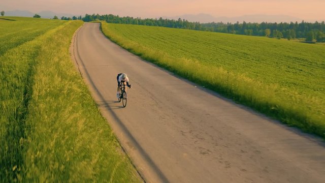 Aerial tracking in front shot of a cyclist on countryside road