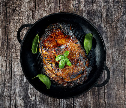 grilled steak in a frying pan on a wooden background