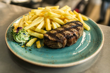 Tender grilled porterhouse steak served with crisp golden French fries and fresh green herb salad by BBQ or herb butter