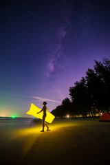 Fototapeta premium man holding glow pillow with milky way and seabeach background