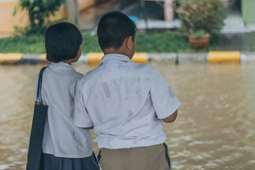 Boy and girl  wait to cross flooded street in heavy rainstorm be