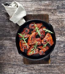 Barbecue on the grill chicken wings in a frying pan on a wooden background
