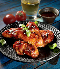 Barbecue on the grill chicken wings on a plate on a wooden background