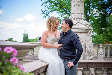 Beautiful blonde bride with a magnificent forms in the garden among the flowers in a long light dress. Bride and groom on the walk 