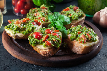 Bruschetta with fresh pesto, mozzarella and cherry tomatoes on cutting board
