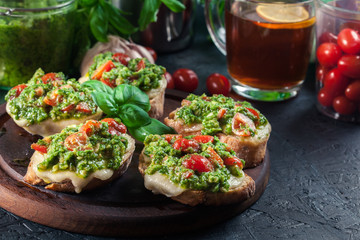 Bruschetta with fresh pesto, mozzarella and cherry tomatoes on cutting board