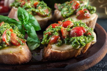 Bruschetta with fresh pesto, mozzarella and cherry tomatoes on cutting board