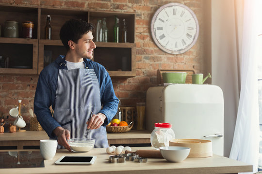 Cheerful young man baking in loft kitchen
