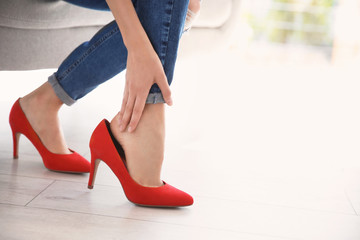 Tired woman with beautiful legs taking off shoes at home, closeup