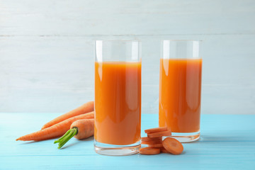 Glasses with carrot juice and fresh vegetable on wooden table