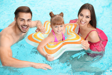 Happy family with inflatable ring in swimming pool