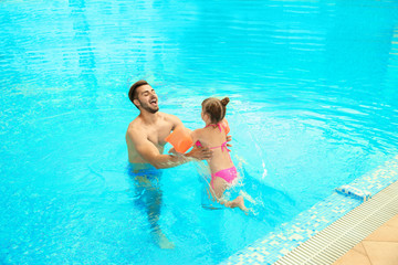 Father and daughter playing in swimming pool