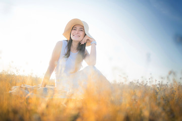 Happy asian woman sitting in meadows with sunset