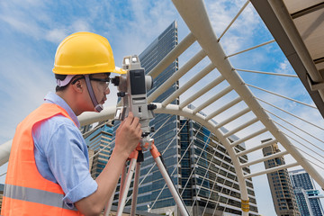 Survey by theodolite concept. Civil Engineer Checking Surveyor Equipment Tacheometer or theodolite outdoors at construction site on the road.
