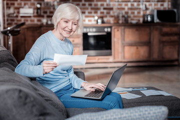 Modern technology. Cheerful blonde female expressing positivity while checking her calculations