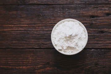 Sugar powder in a bowl on the wooden surface
