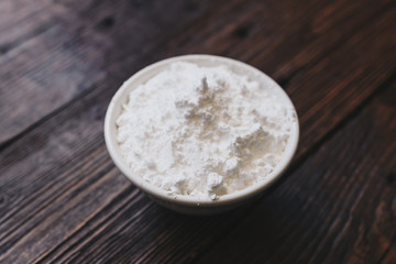 Sugar powder in a bowl on the wooden surface