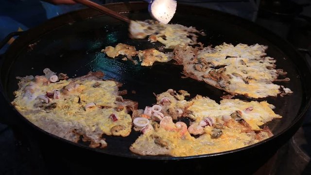 Street trade food : cooking fried mussel pancakes or oyster omelette on the street night market in island Koh Phangan, Thailand. Close up