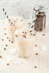 Summer cold Iced coffee frappe with milk and ice cubes, light concrete background copy space