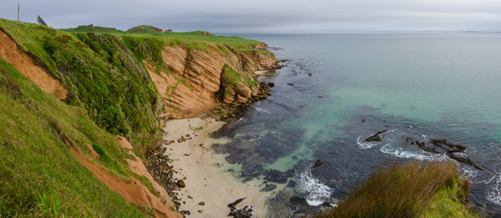 Obraz premium Elevated view of red sandstone cliffs and a small beach on the Chatham Islands, New Zealand. 